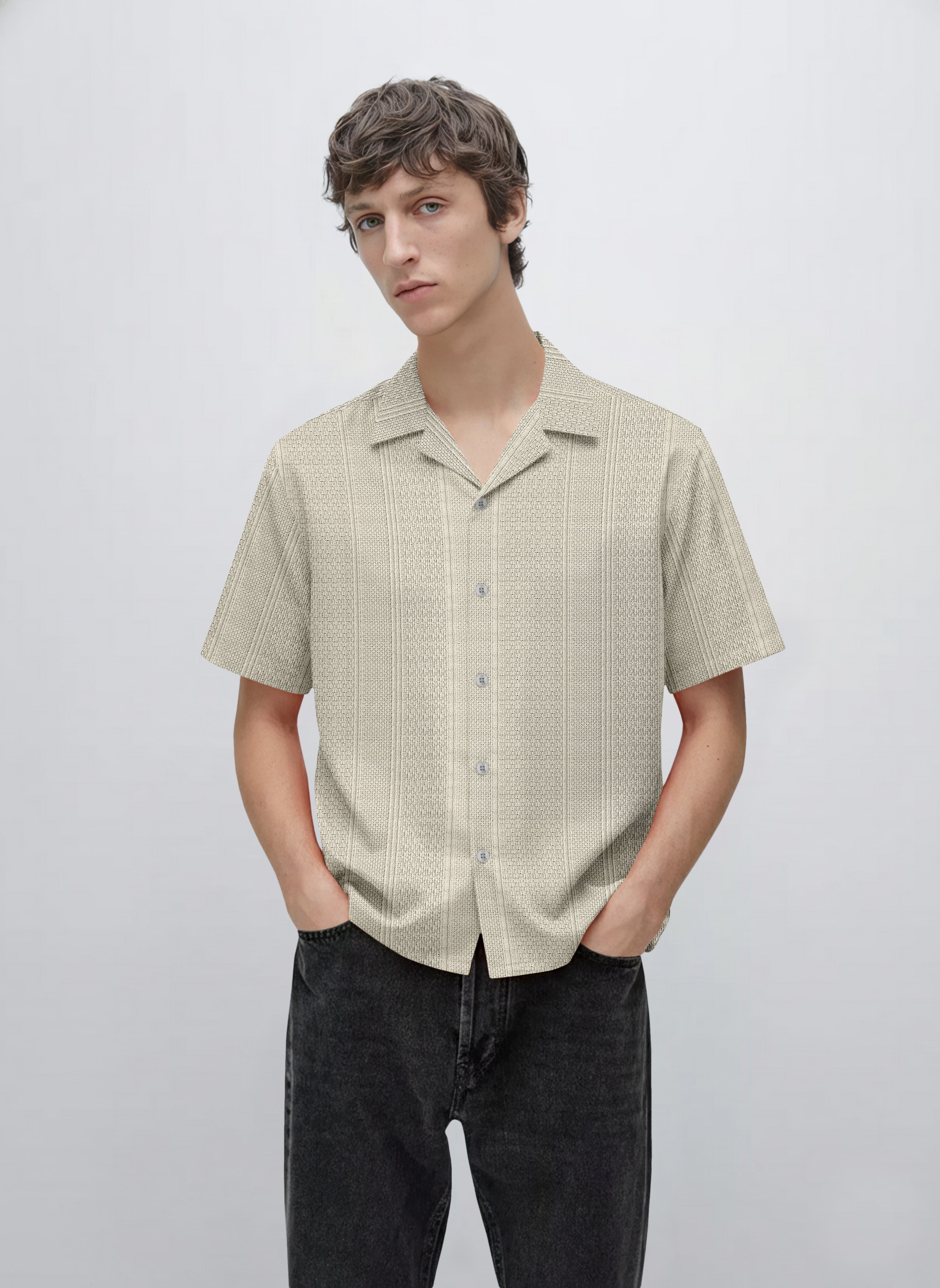 Man wearing a beige short sleeve button-up patterned shirt with black jeans