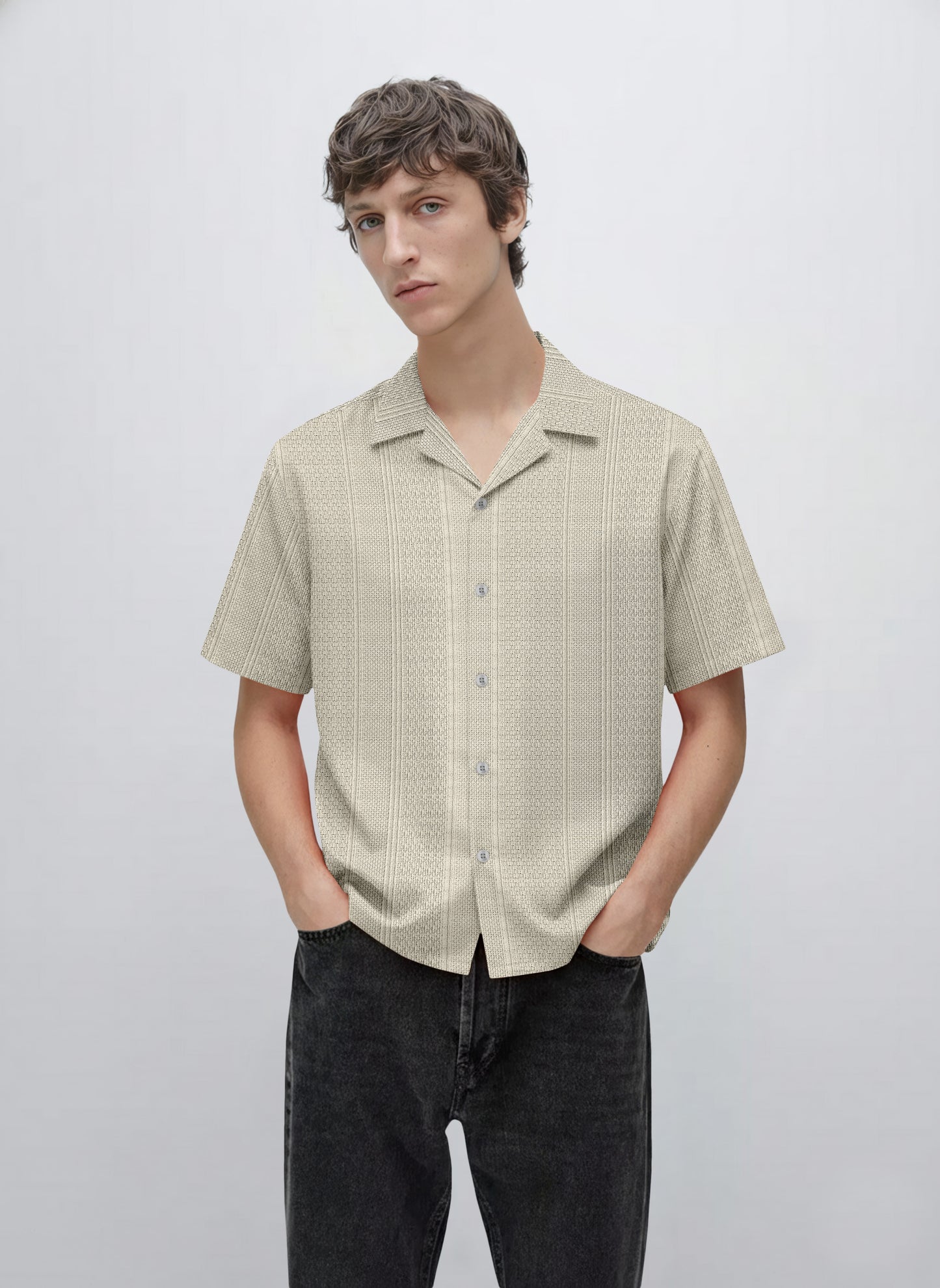 Man wearing a beige short sleeve button-up patterned shirt with black jeans
