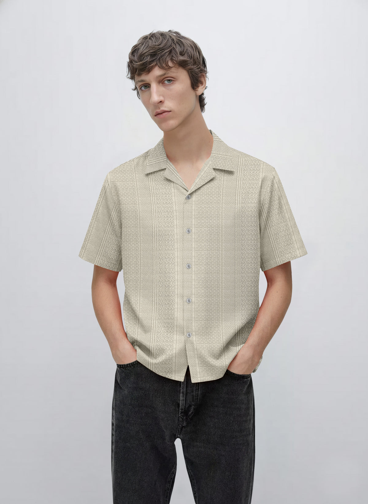 Man wearing a beige short sleeve button-up patterned shirt with black jeans