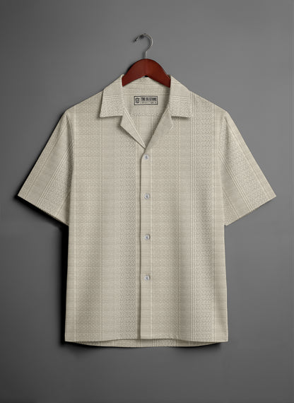 Beige short sleeve button-up shirt with subtle textured pattern on hanger, grey background