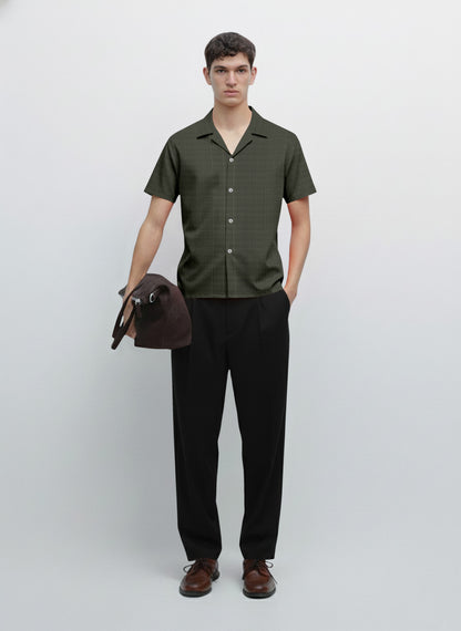 Man wearing short sleeve button-up shirt, black trousers, brown shoes, holding bag