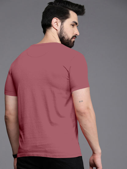 Man wearing plain mauve short sleeve t-shirt, viewed from the back, with 11:11 tattoo on arm.