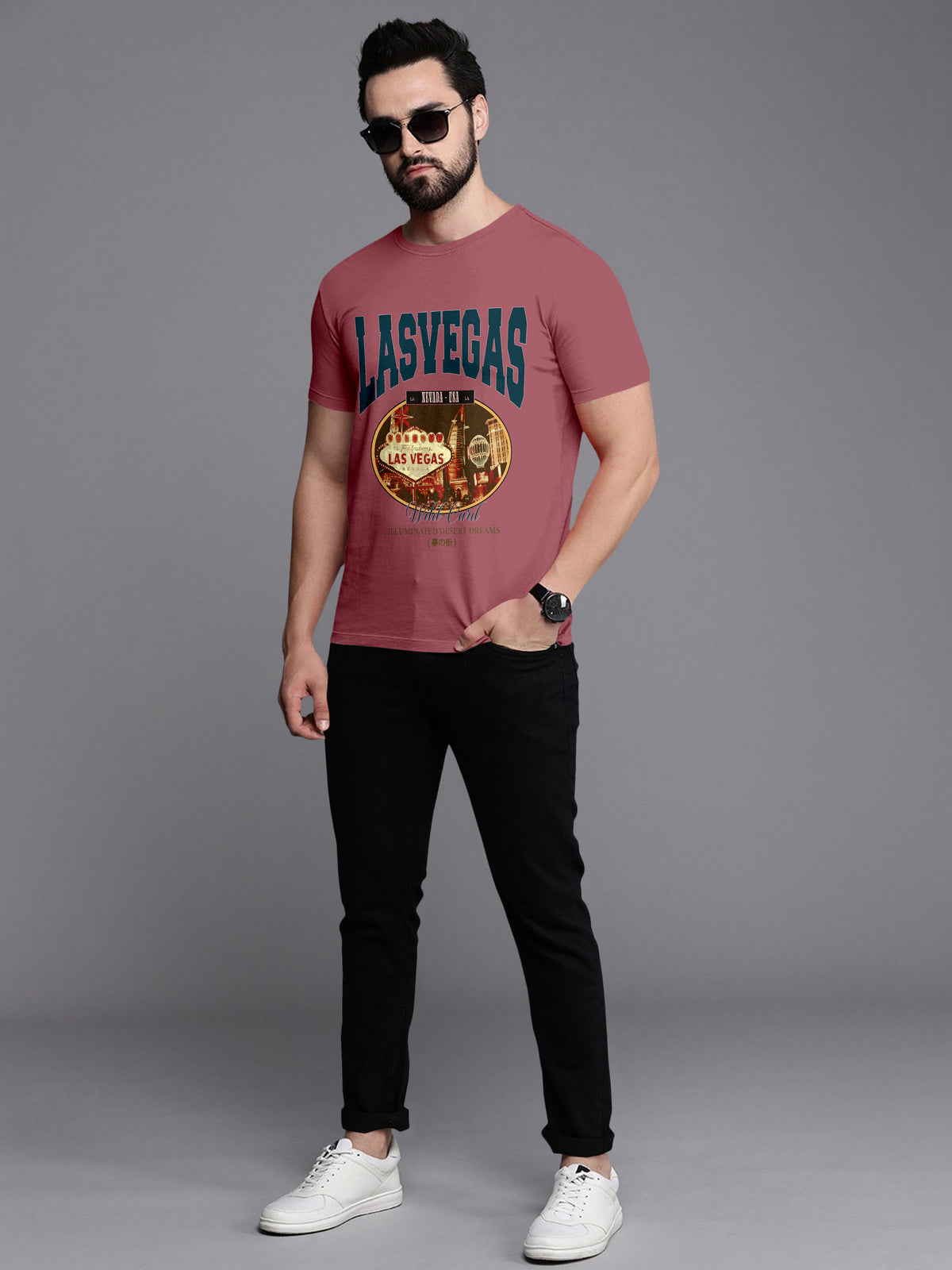 Man wearing pink Las Vegas graphic t-shirt, black jeans, white sneakers, and sunglasses