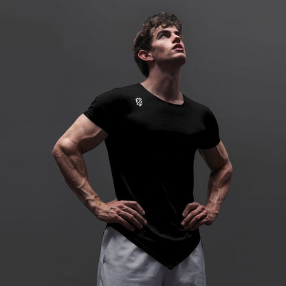 Man in black athletic t-shirt with logo, white shorts, posing against plain gray background