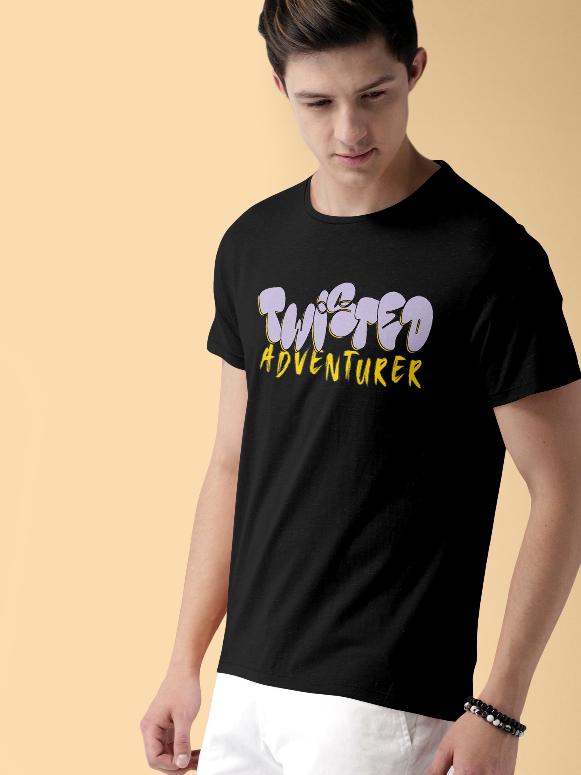 Man wearing black Twisted Adventurer graphic t-shirt on beige background.