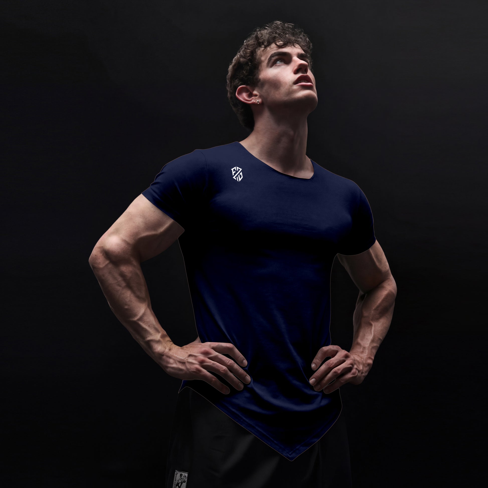 Athletic man in fitted navy blue gym t-shirt with logo, posing against dark background