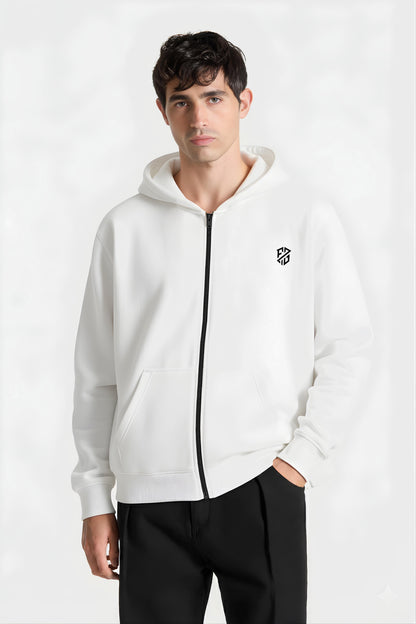Man wearing white zip-up hoodie with black logo and black pants, studio background