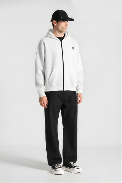 Man in white zip up hoodie, black pants, black cap, and platform sneakers on white background