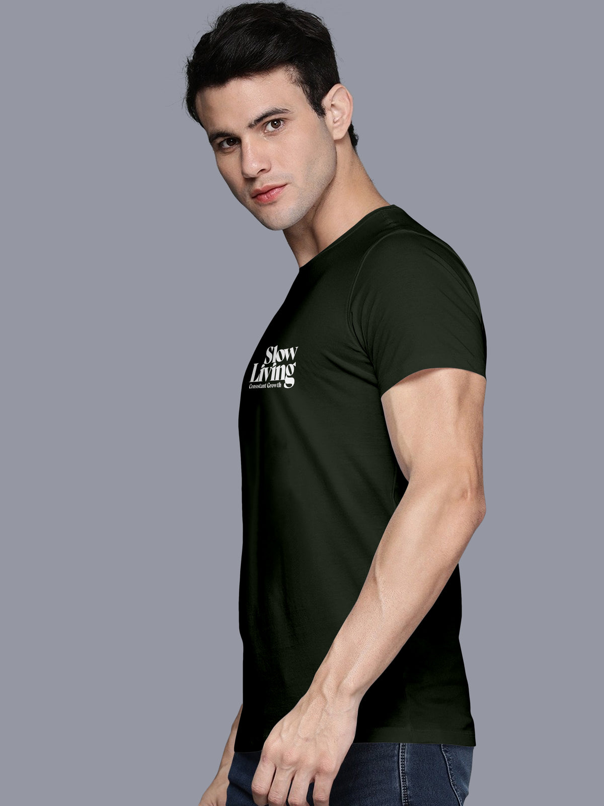 Man wearing black 'Slow Living' slogan t-shirt and blue jeans on a plain background